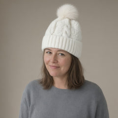 Woman wearing the cable knit bobble hat, faux fur pompom, full length, studio