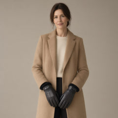 Woman in a camel coat wearing black goatskin leather gloves with finger seams and a snap wrist strap