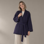 Woman wearing the belted wrap wool coat, fringed hem, three-quarter view, studio