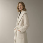 Woman wearing an ivory shawl-collar wrap coat, three-quarter turn, hands in the pockets