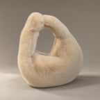 Women’s Faux Fur Dumpling Bag, Top Handle, laid flat on a stone backdrop