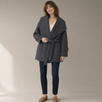Woman wearing the belted wrap coat, oversized fold collar, three-quarter view, studio