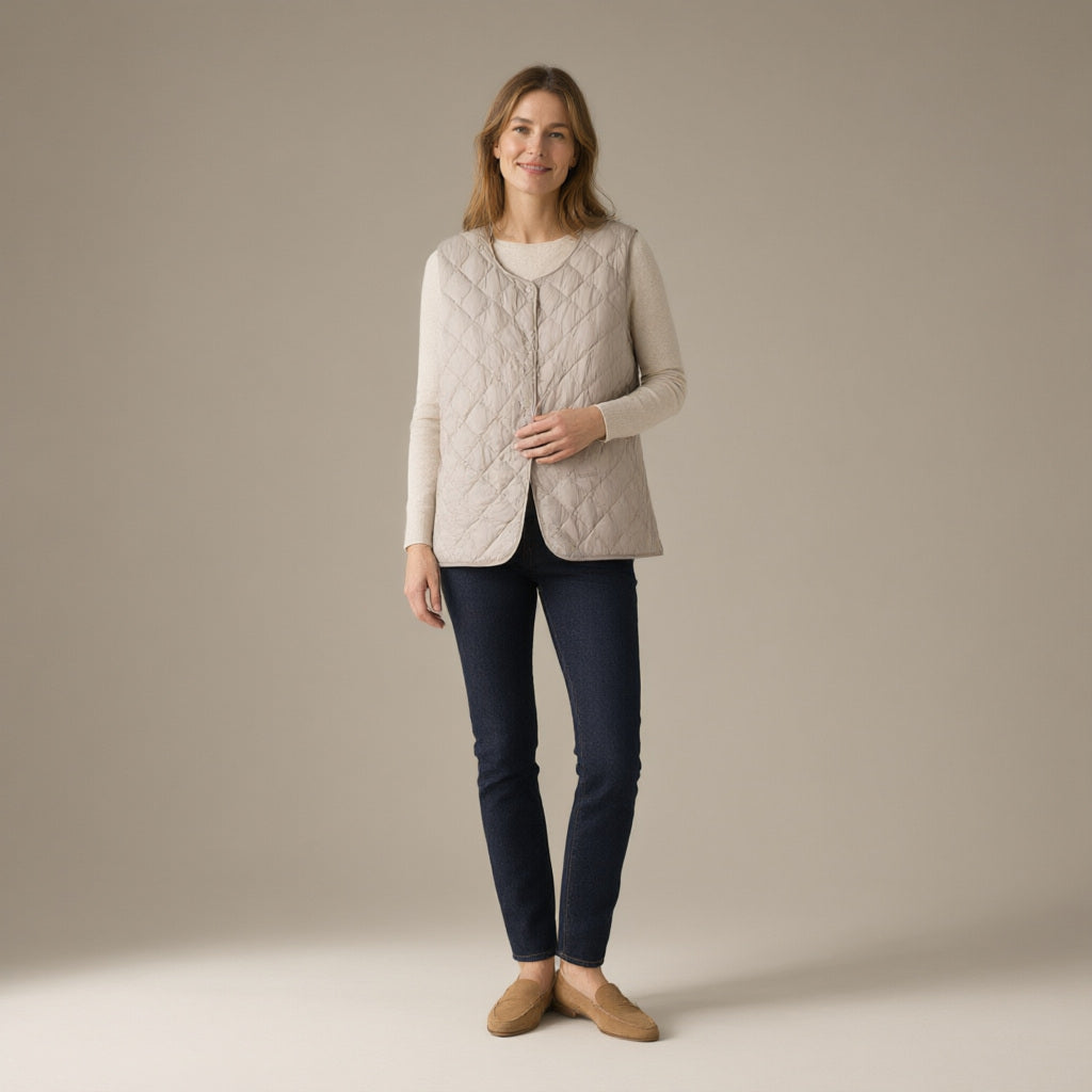 Woman wearing a stone quilted gilet over a cream knit and dark jeans, full length