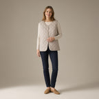 Woman wearing a stone quilted gilet over a cream knit and dark jeans, full length
