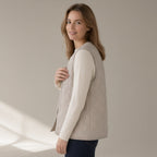 Woman wearing a stone quilted gilet over a cream knit, three-quarter turn