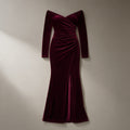 Women’s off-shoulder velvet mermaid gown in wine, long sleeve, laid flat on a stone backdrop