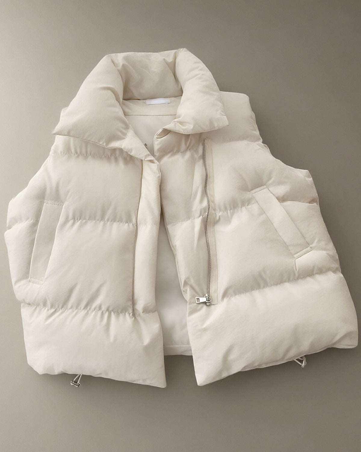 Women’s Short Padded Gilet – Cream, Black or Mocha, laid flat on a stone backdrop