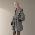 Woman wearing the hooded patchwork coat with knit cuffs, tie belt, three-quarter view, studio
