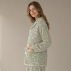 Woman wearing a sage green floral flannel fleece pyjama top, three-quarter turn, hands in the pockets