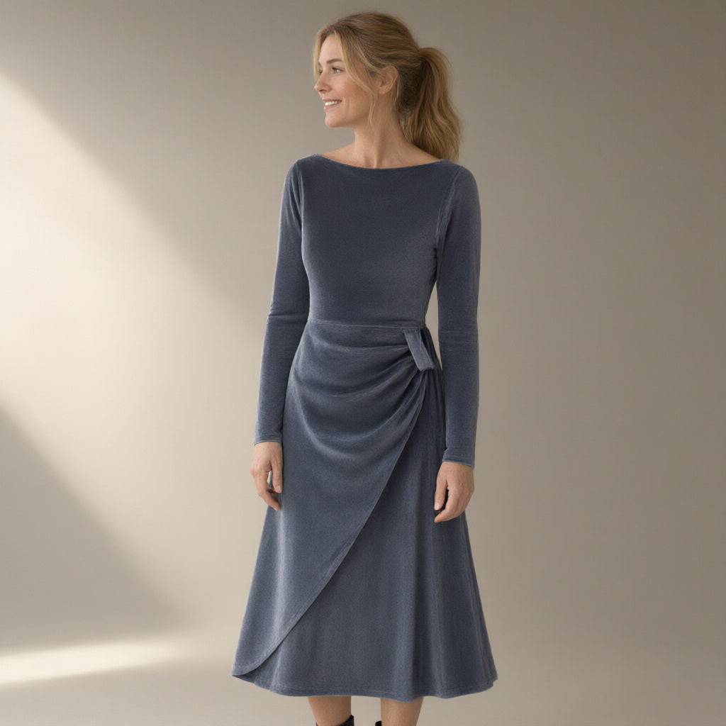 Woman wearing the twist-waist velvet evening dress, long sleeve – slate grey, three-quarter view, studio