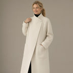 Woman wearing the long wrap coat, stand collar & tie belt, three-quarter view, studio