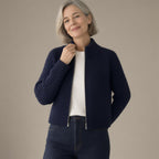 Woman wearing the zip-up ribbed knit cardigan, stand collar – navy, three-quarter view, studio